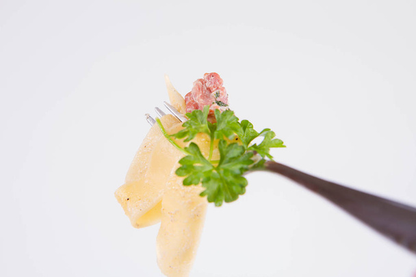Pappardelle Carbonara with some parsley on a fork on a white background - Photo, Image