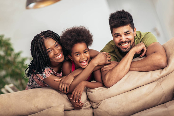 Boldog család pózol a kanapén együtt otthon a nappaliban - Fotó, kép