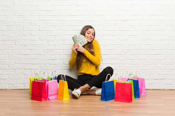 Young girl with lot of shopping bags taking a lot of money - Foto, Imagem