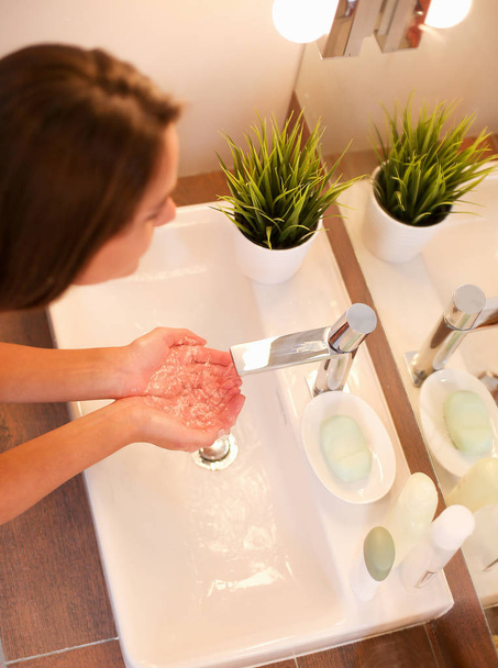 Jeune femme se lave le visage avec de l'eau propre dans la salle de bain - Photo, image