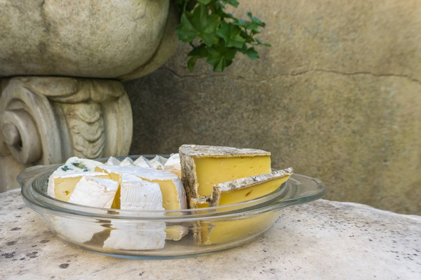 Různé druhy lahodných sýrů v skleněnou desku na kamenný stůl v retro exteriér - Fotografie, Obrázek