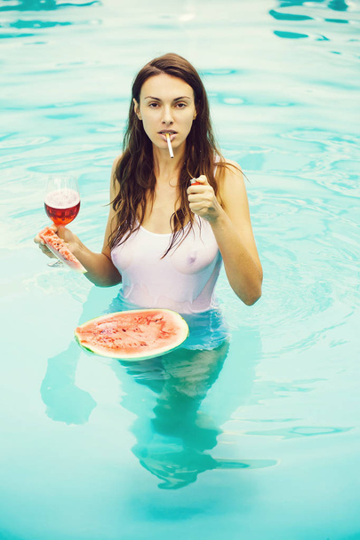 girl smoking with watermelon and wine in pool - Foto, imagen