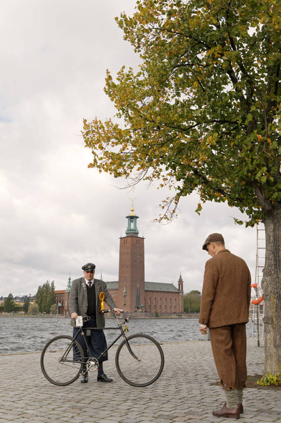 СТОКГОЛЬМ - 22 сентября 2018 года: Человек в старомодном твидовом костюме и шляпе с ретро-велосипедом перед зданием мэрии Стокгольма на велосипеде в Твиде 22 сентября 2018 года в Стокгольме, Швеция
 - Фото, изображение