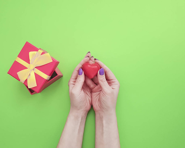 female hand manicure, gift box, heart on colored background - Zdjęcie, obraz