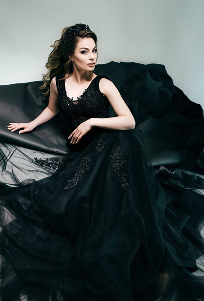 Beautiful young woman in black dress  posing  in studio - Фото, изображение