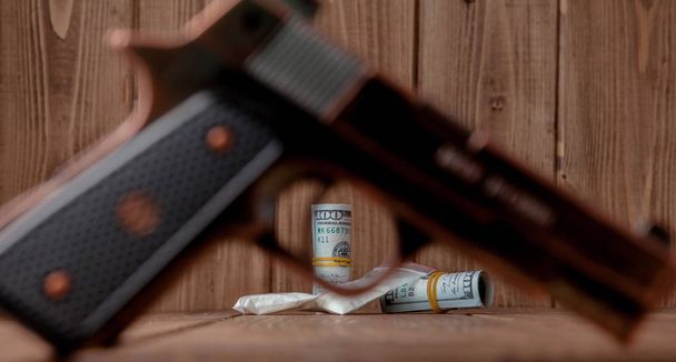 Stack of Money, drugsand a gun on a wooden table, concept about danger and threat of the drug. - Foto, Imagen