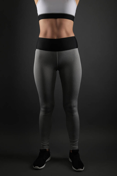 Jeune femme de fitness en vêtements de sport sur fond noir - Photo, image