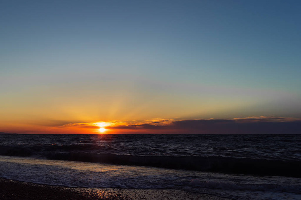 Naplemente a tengerparton. Eltérő sugarait a nap a felhők között. Kis tenger hullámai. Szép estét táj. - Fotó, kép