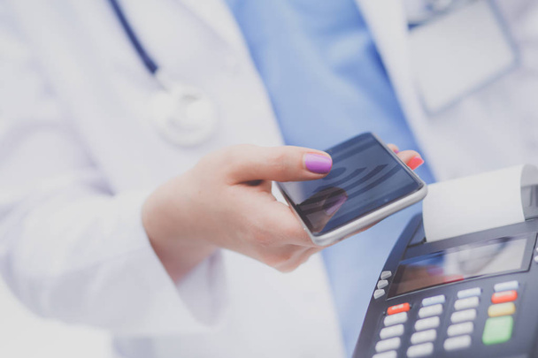 Doctor is holding payment terminal in hands. Paying for health care. Doctor - Foto, Bild