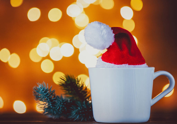 Taza blanca de té o café y luces de Navidad en el fondo
 - Foto, Imagen