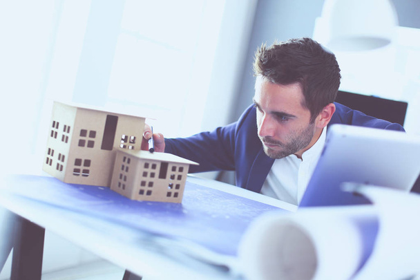 Businessman holding house miniature on hand standing in office. - Photo, Image