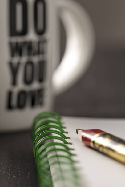 Натюрморт с ручкой и белой кружкой кофе над черным офисным столом. Символ работы
 - Фото, изображение