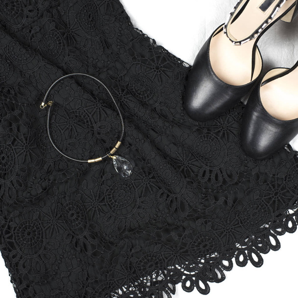 Petite robe en dentelle noire, talons hauts noirs avec des cristaux sur les bretelles et un collier
 - Photo, image