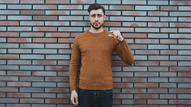 Hipster sms texting phone app in city street on brick wall background. Amazing man holding smartphone in smart casual wear standing. - Foto, Imagen
