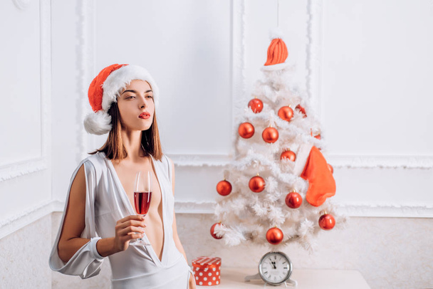Christmas woman. We wish you a merry christmas. Pretty woman in red Santa Hat on holiday. Happy new year. - Foto, imagen