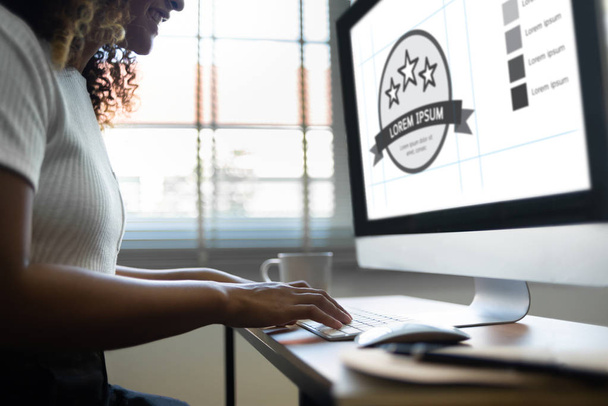 Mulher Africano-Americana sorrindo trabalhando no computador. Designer feminino criativo feliz está fazendo design gráfico enquanto sentado no estúdio de escritório
. - Foto, Imagem