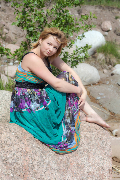 girl in a bright dress sitting on a stone - Foto, immagini