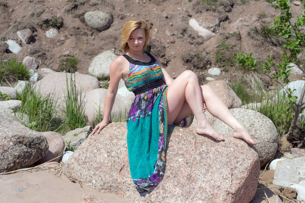 chica en un vestido brillante sentado en una piedra
 - Foto, Imagen