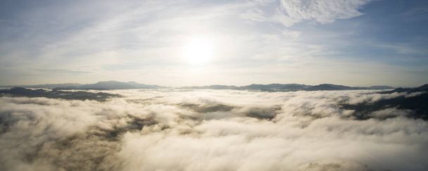 Panorama image Drone shot of Beautiful scenery sunlight in the morning sunrise above flowing fog waves on mountain tropical rainforest in phang nga thailand. - Foto, imagen
