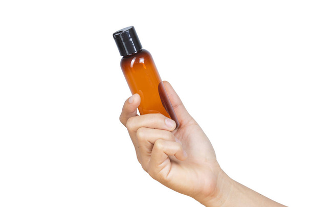 Hand holding brown spray bottle isolated on white background with clipping path. - 写真・画像