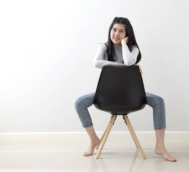 Attractive Asian girl sitting on black modern chair and relax at home - Foto, immagini