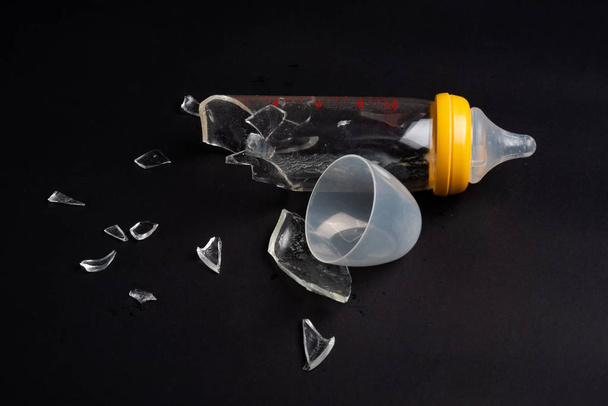 broken glass baby bottle on dark background - Foto, Bild