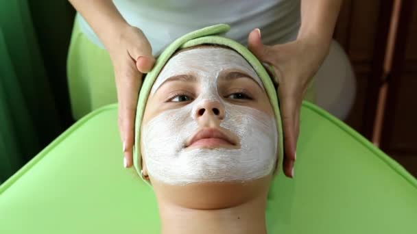 ręce kosmetyczki poprawić Zielona opaska na głowę dziewczyny po nałożeniu kremu na twarzy - Materiał filmowy, wideo