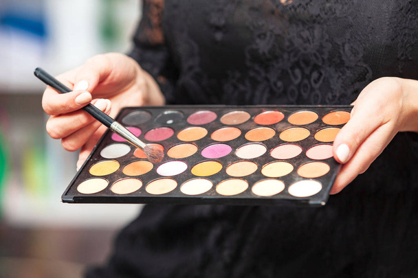 Closeup shot of palette of an eye shadows in hands of a makeup specialist - Foto, Bild