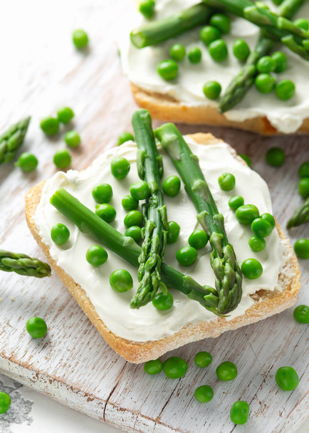 Appetizer bruschetta, toast with Asparagus, Peas and creamy soft cheese on white board. healthy food. - Photo, Image