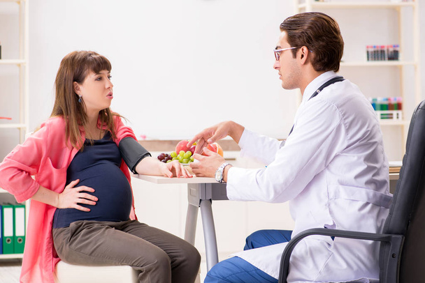 Беременная женщина посещает врача, обсуждая здоровую диету
 - Фото, изображение