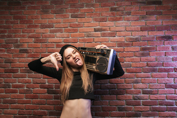 Зображення модного хіп-хоп жінки 20 стоїть на стіні цегли і тримає бумбокс
 - Фото, зображення