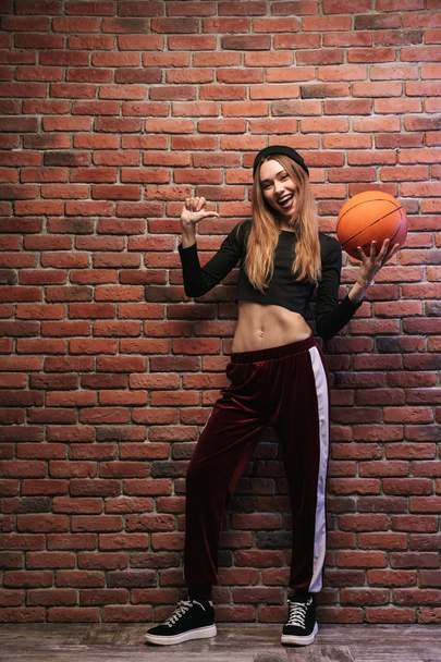 Full length photo of young sporty girl standing against brick wall with basketball - Foto, immagini