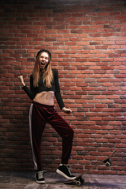 Full length photo of pretty sporty girl standing against brick wall with skateboard - Φωτογραφία, εικόνα