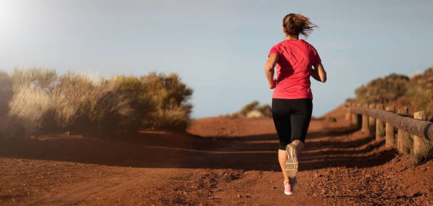 Fitness woman runner athlete running at road, working out cardio on nature landscape - Photo, Image