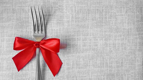 Decoración festiva de mesa. Tenedor con lazo rojo. Foto para el menú de cafetería, restaurante, comedor, pizzería. Un lugar para un menú festivo
. - Foto, imagen