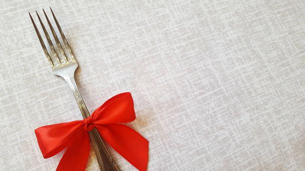 Festive table decoration. Fork with a red bow.  Photo for the menu of cafe, restaurant, dining room, pizzeria. A place for a festive menu. - Photo, image