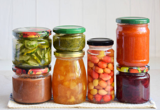 Variedad de alimentos conservados en frascos de vidrio: encurtidos, mermelada, mermelada, salsas, ketchup. Conservación de verduras y frutas. Comida fermentada. Enlatado de otoño. Conservación de la cosecha
. - Foto, Imagen
