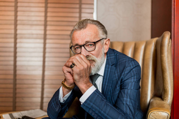 Ηλικιωμένος επιχειρηματίας με επίσημο κοστούμι με ουίσκι και πούρο στο πολυτελές εσωτερικό - Φωτογραφία, εικόνα