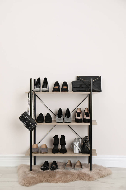 Shelving unit with stylish shoes and purses near white wall. Element of dressing room interior - Foto, afbeelding