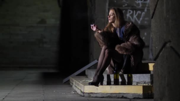 Генеральний план. Сексуальна дівчина в шубці сидить на сходах курить і п'є вино. П'яна самотня жінка в нічному місті 4K Slow Mo
 - Кадри, відео