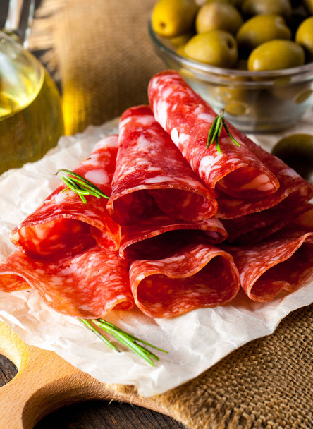 Italian salami with olives and spices on wooden background - Fotografie, Obrázek