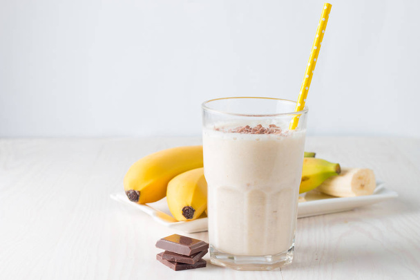 Fresh Made Chocolate Banana Smoothie on a wooden table. Selective focus. Milkshake with almonds. Protein diet. Healthy food and drink concept. - Photo, Image
