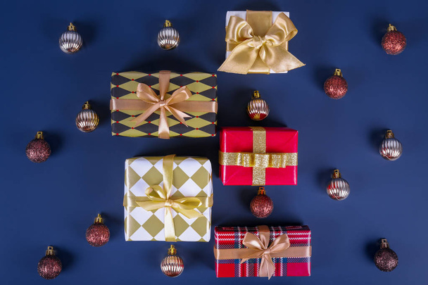 Festive composition with colorful Christmas presents wrapped in bright paper tied with bow on solid blue background. New year themed flat lay with festive attributes. Close up, copy space. - Zdjęcie, obraz