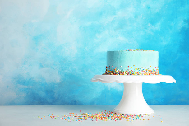 Fresh delicious birthday cake on stand against color background. Space for text - Фото, зображення