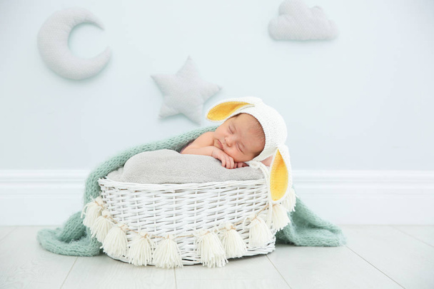 Adorable newborn child wearing bunny ears hat in baby nest indoors - Fotó, kép