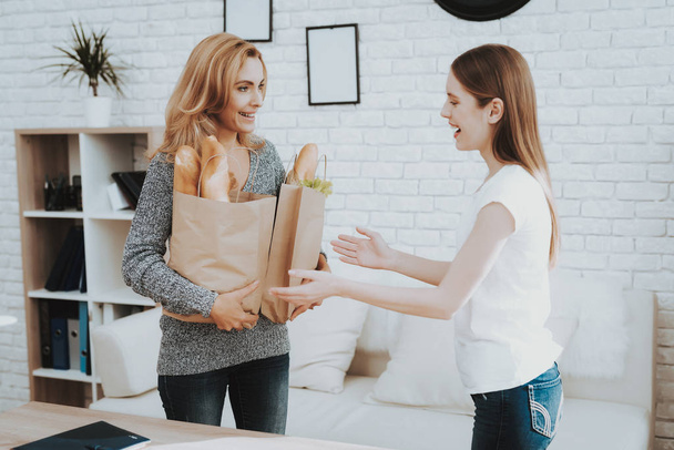 Mother with Packs of Food from Store at Home. Daughter Helping Mother. Healthy Food and Lifestyle Concept. Cooking Together. Bread in Bag. Mother and Daughter at Home. Teenage Girl. - 写真・画像