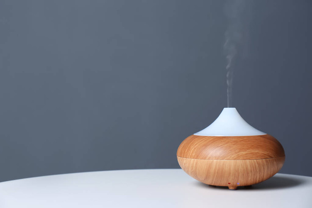 Aroma oil diffuser lamp on table against gray background. Space for text - Φωτογραφία, εικόνα