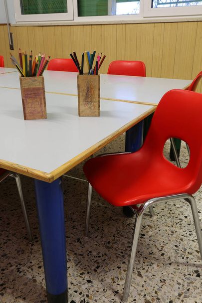 学校と多くの鉛筆テーブルの上のクラスの部屋で赤い椅子 - 写真・画像