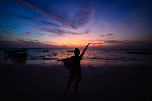 Nainen tanssimassa hiekkarannalla romanttinen taivas auringonlaskussa, takana näkymä, kultainen auringonvalo, oikeita ihmisiä. Indonesia, Kei saaret, Molukit Maluku
 - Valokuva, kuva