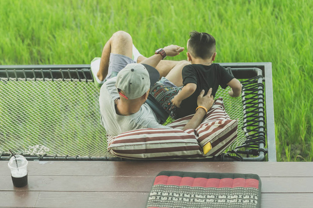 Папа и сын отдыхают на балконе с красивыми рисовыми полями
. - Фото, изображение